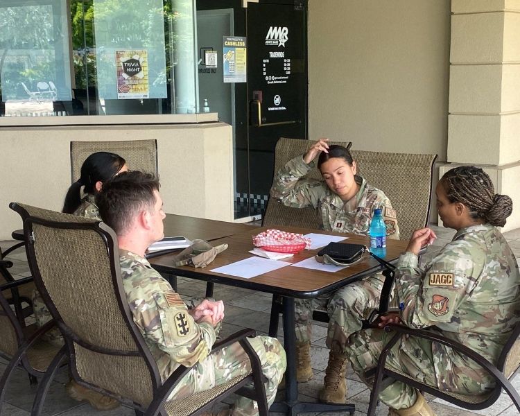 Photo of uniformed service members sitting outside having mentorship discussions.