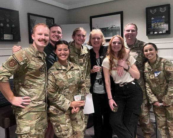 Group photo of uniformed service members and plain clothed individuals smiling.