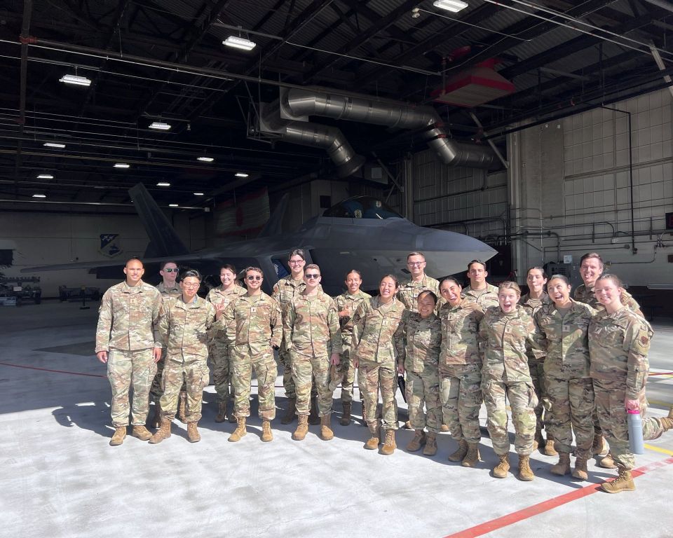 Outdoor group photo of uniformed service memebrs in front of an F-35 in a hanger.