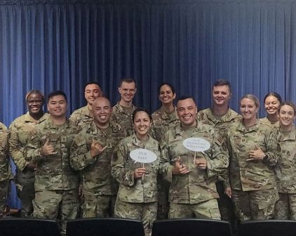 Indoor group photo of uniformed service members  holding talk bubble signs.